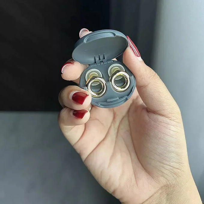Hand holding a pair of Loop Switch Gold earplugs in the case