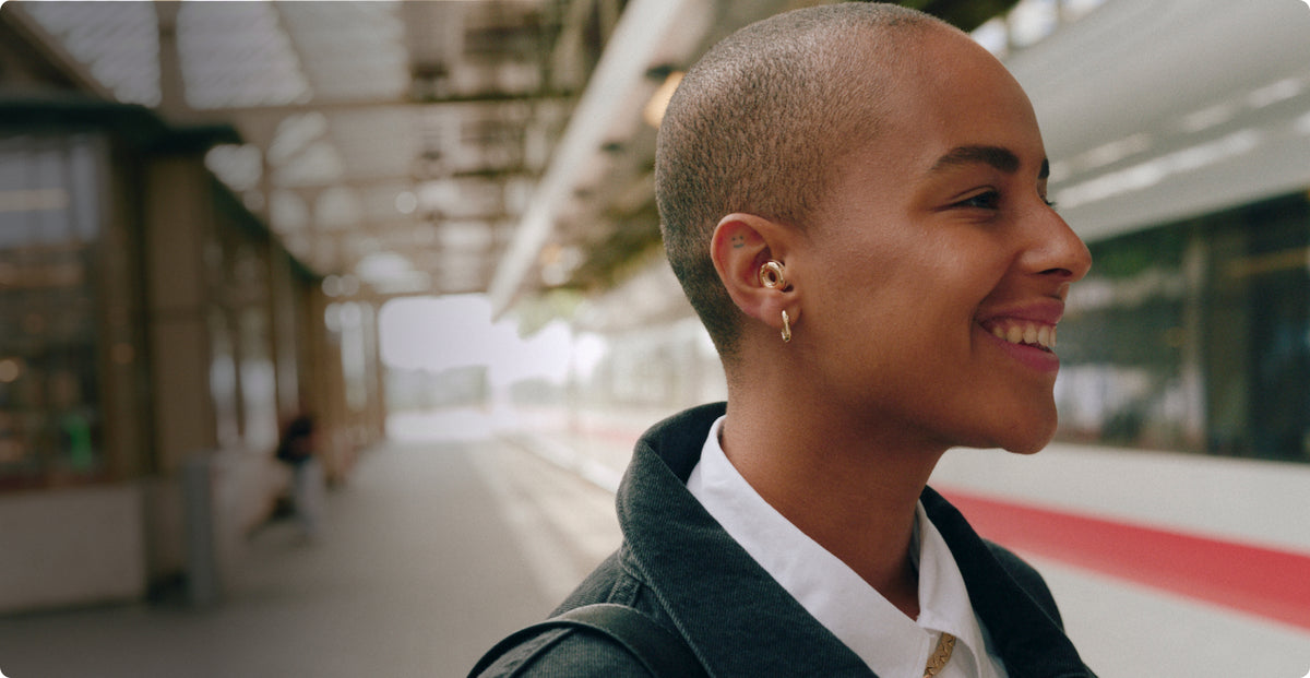 Woman smiling outdoors in a train station wearing Loop Switch earplugs