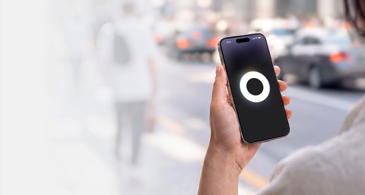 Hand holding a smartphone with the Loop Sphere app icon on a blurred city street background